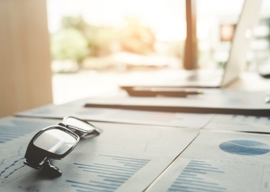 Glasses and investment charts sitting on table in sunny room